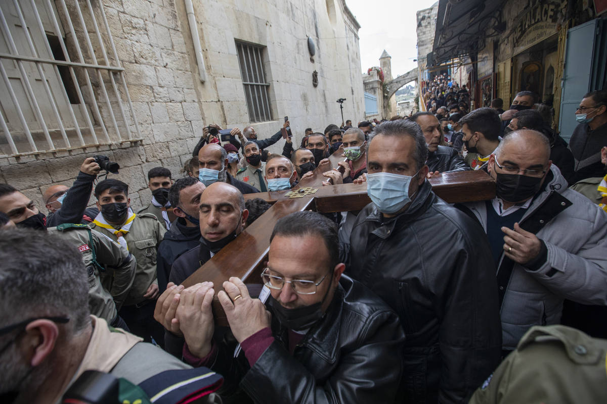 Christians carry a cross along the Via Dolorosa towards the Church of the Holy Sepulchre, tradi ...