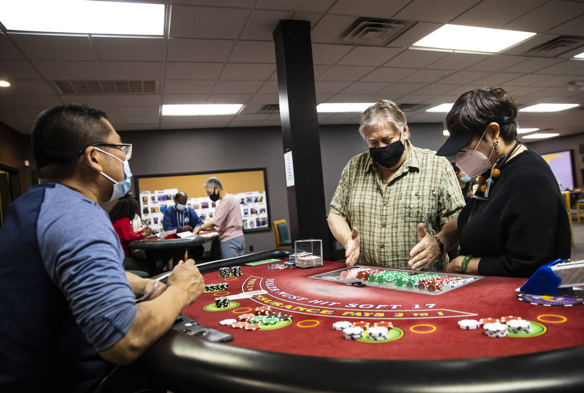 Instructor Ray Nichols, center, assists students Steven Chen, left, and Grace Ho at a blackjack ...