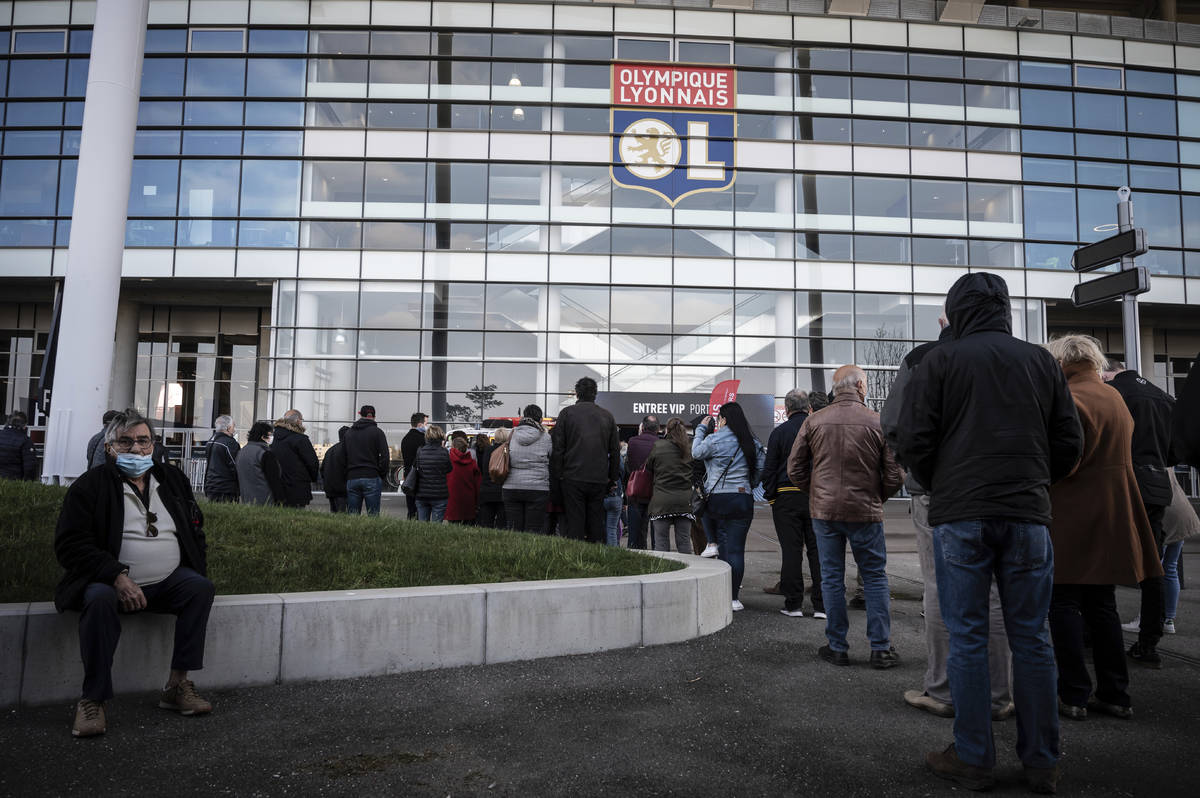 People wait outside as they arrive to be vaccinated against Covid-19 the opening day of a mass ...