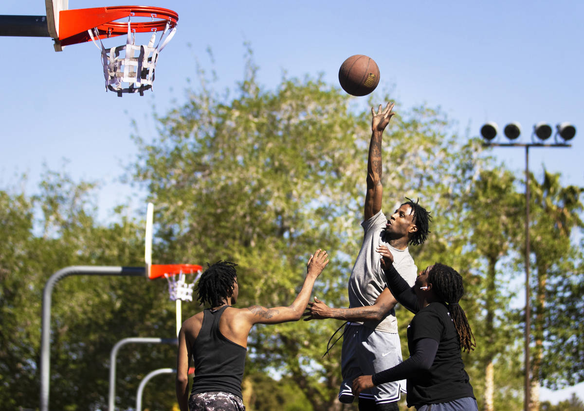 Denzel Carter, top/right, shoots a runner over Devion Williams, right, and Jason Ford at Sunset ...