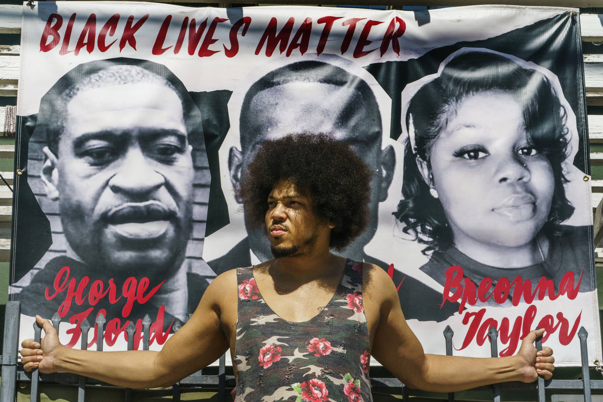 Actor Steven Thompson poses for a picture next to a poster of George Floyd in Los Angeles Frida ...