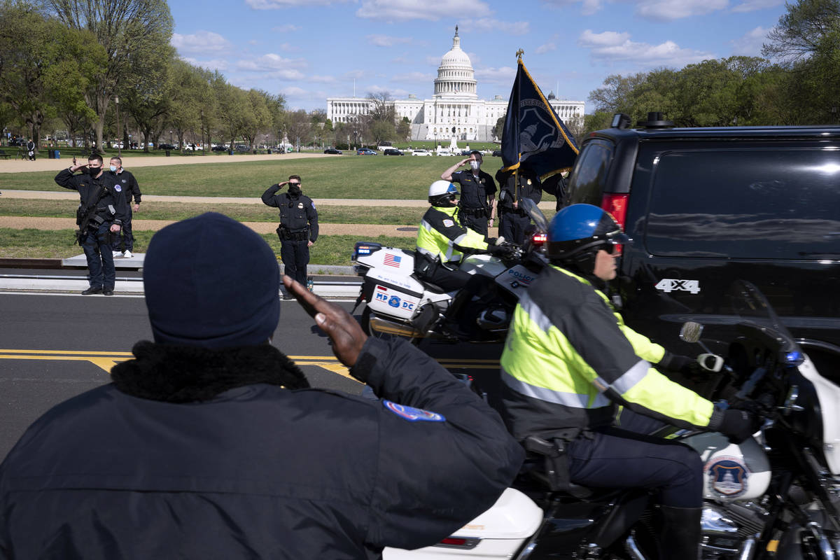 With the U.S. Capitol in the background, U.S. Capitol Police officers salute as procession carr ...