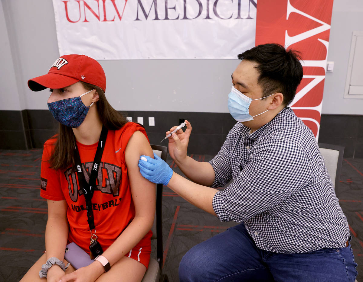 UNLV volleyball player Kate Brennan, 20, gets a COVID-19 vaccination from Andrew Choi at the UN ...
