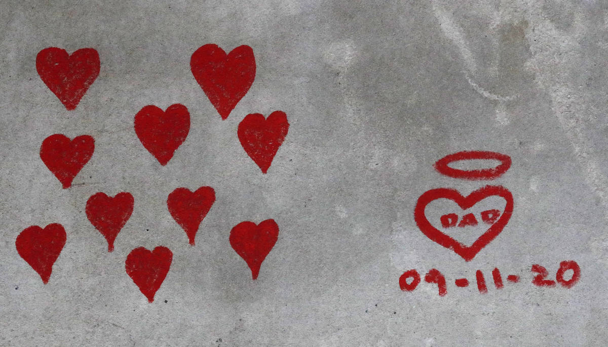 Red hearts are painted on the COVID-19 Memorial Wall mourning those who have died, opposite the ...