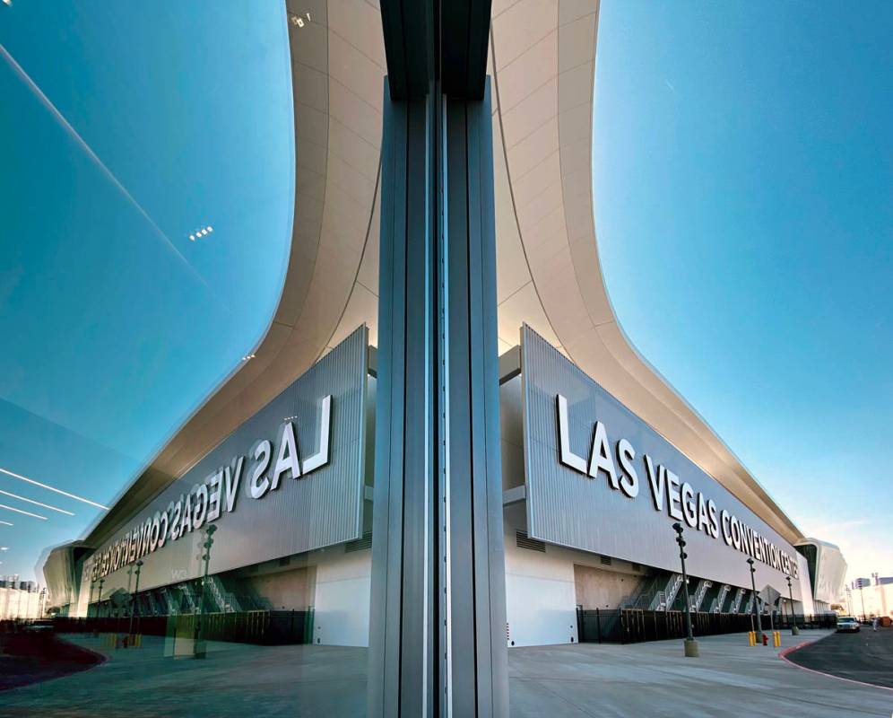 Signage is reflected in a glass door on the side of the building outside the new Las Vegas Conv ...