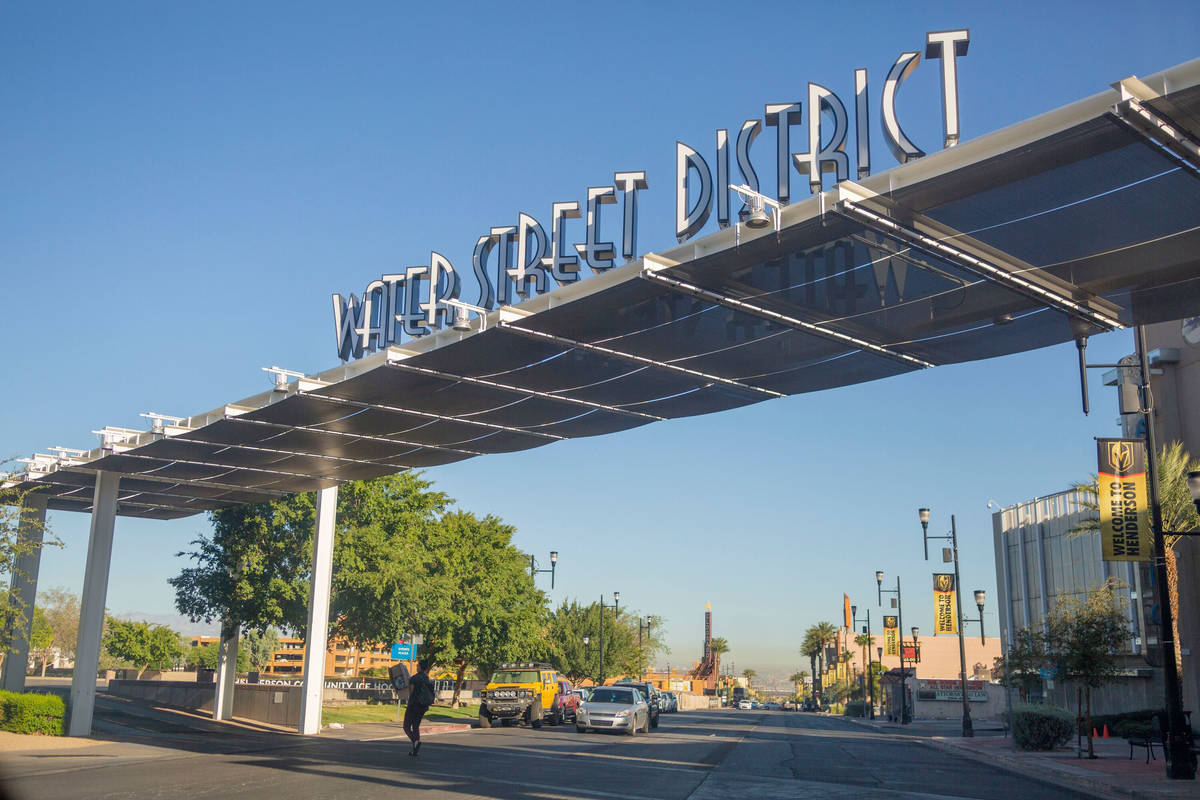 A pedestrian crosses underneath a sign identifying the iconic Water Street District on South Wa ...