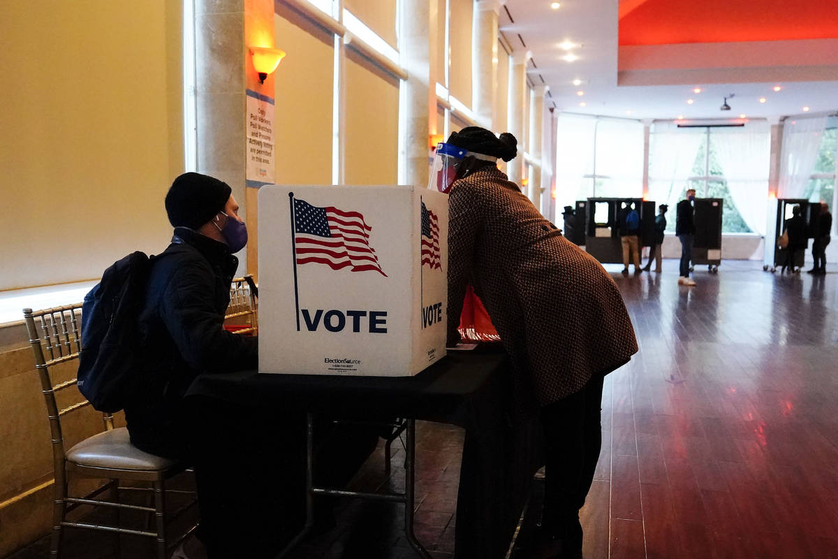 In this Nov. 3, 2020, file photo, a poll worker talks to a voter before they vote on a paper ba ...