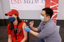 UNLV volleyball player Kate Brennan, 20, gets a COVID-19 vaccination from Andrew Choi at the UN ...