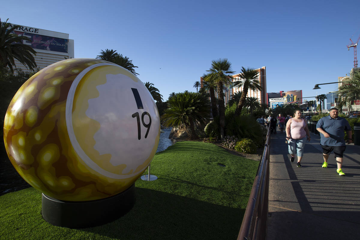 Pedestrians pass a 200-pound bingo ball by artist Jerry Misko, displayed in front of The Mirage ...