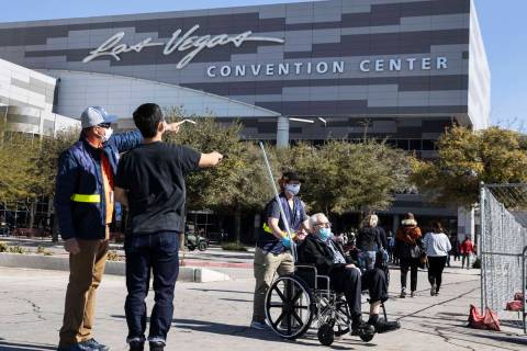 A FEMA employee directs people to the Las Vegas Convention Center's vaccine distribution area w ...