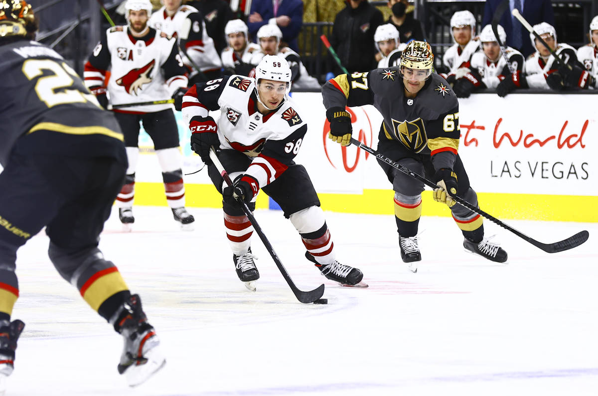 Arizona Coyotes' Michael Bunting (58) skates with the puck under pressure from Golden Knights' ...