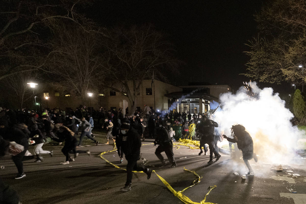 People run as police attempt to disperse the crowd at the Brooklyn Center Police Department, la ...