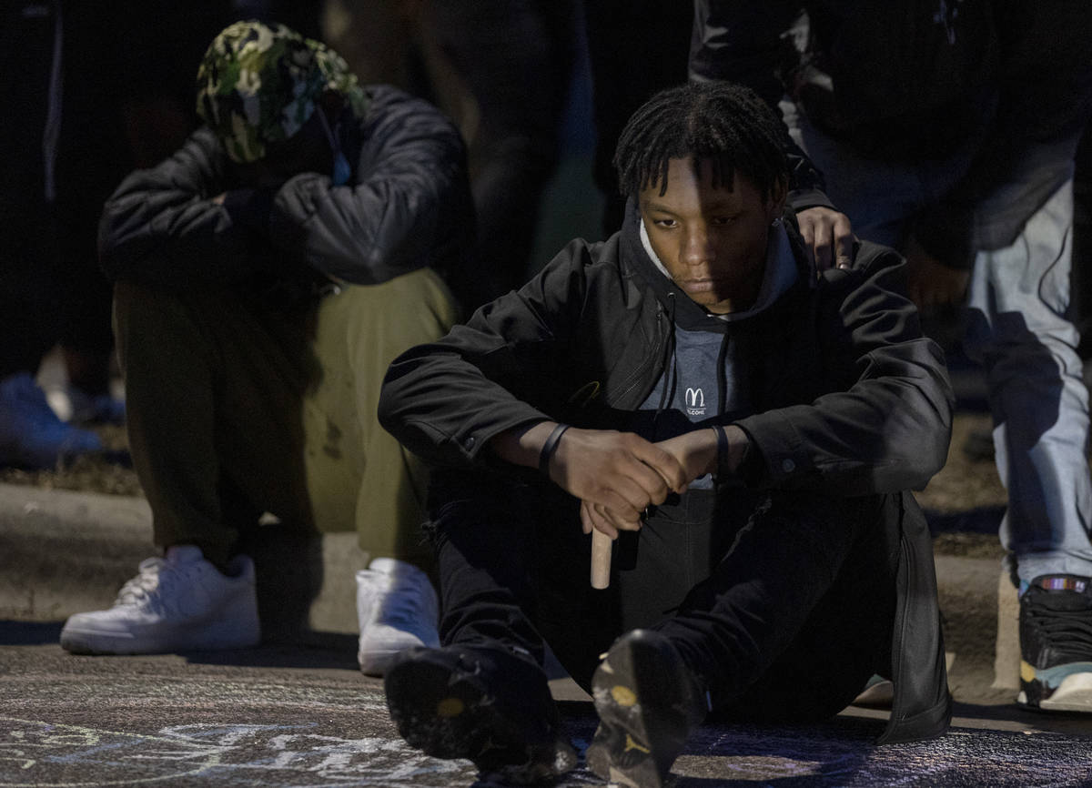 A man sits near a circle around a memorial for Daunte Wright in Brooklyn Center, Minn., Sunday, ...