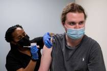 Cole Smith receives a Moderna variant vaccine shot from clinical research nurse Tigisty Girmay ...