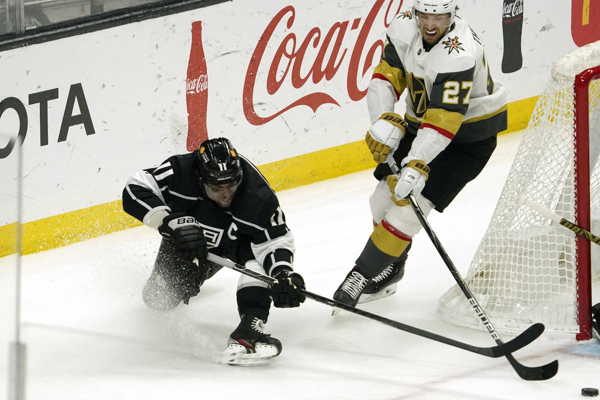 Los Angeles Kings center Anze Kopitar, left, falls as he moves the puck while under pressure fr ...