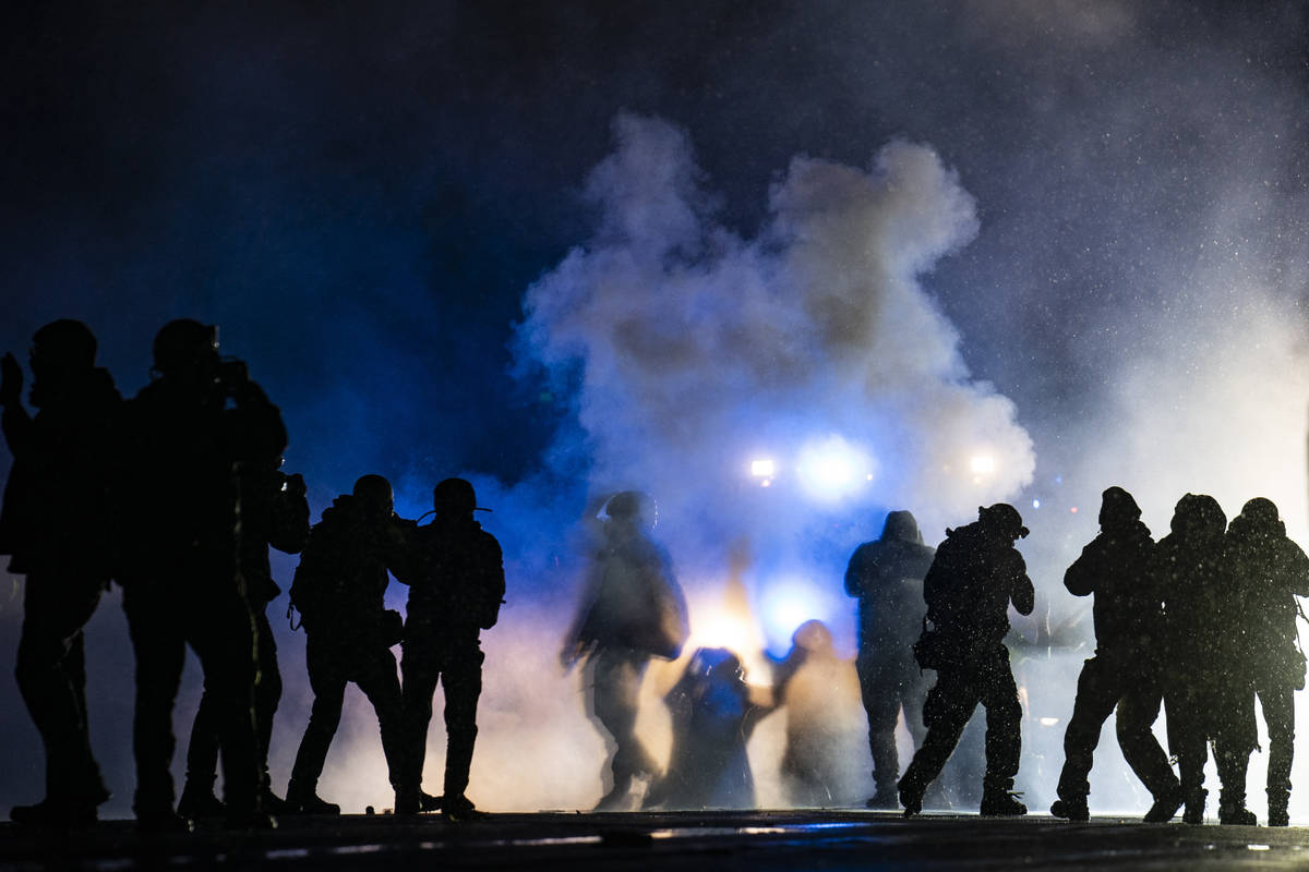 Authorities fire gas munitions at demonstrators gathered outside the Brooklyn Center Police Dep ...
