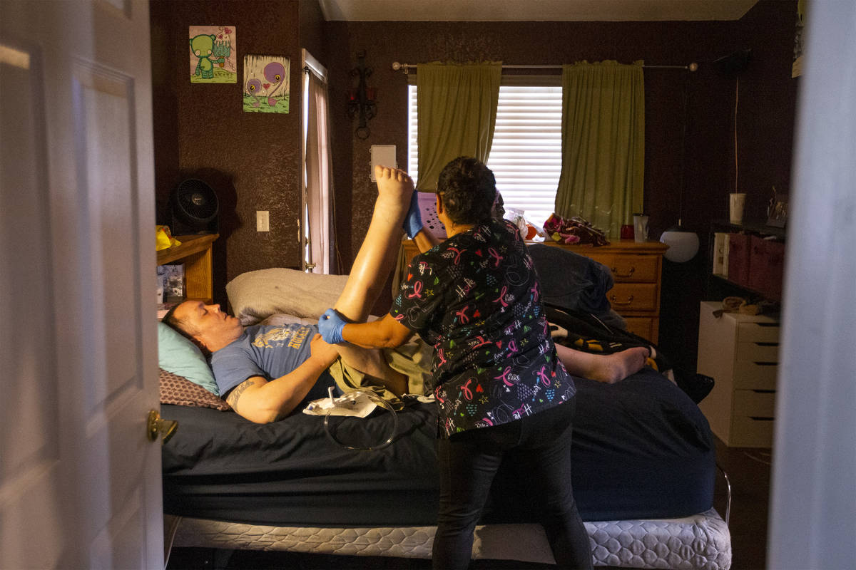 Personal care aid Irma Nuñez stretches her client Thomas Draa's legs on Wednesday, April 14, 2 ...