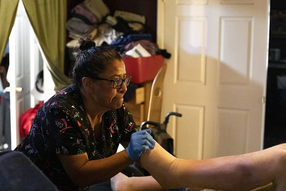 Personal care aid Irma Nuñez stretches her client Thomas Draa's legs on Wednesday, April 14, 2 ...