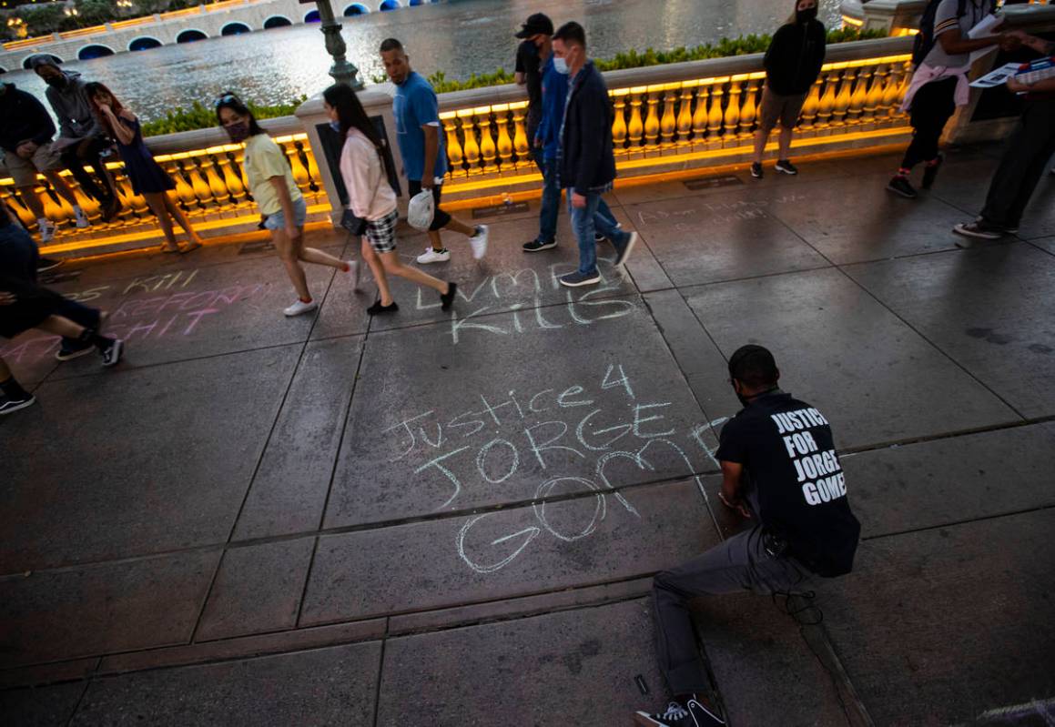 A man who declined to provide his name writes in chalk on the sidewalk outside of the Bellagio ...