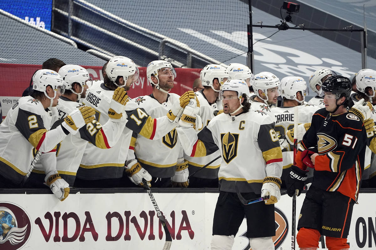 Vegas Golden Knights right wing Mark Stone, center right, high-fives teammates on the bench aft ...