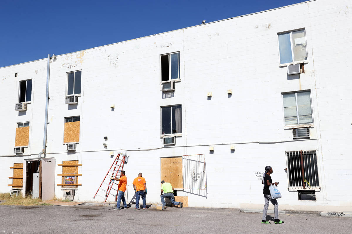 Workers board up windows at the Alpine Motel Apartments in downtown Las Vegas Thursday, Oct. 15 ...