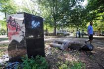 In this June 1, 2020, file photo, an unidentified man walks past a toppled statue of Charles Li ...