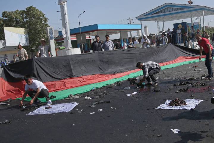 Afghans gather property, left behind by victims of a deadly explosion that struck a protest mar ...