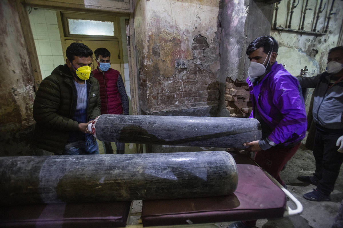 Attendants of a patient carry an oxygen cylinder for the patient inside a hospital in Srinagar, ...
