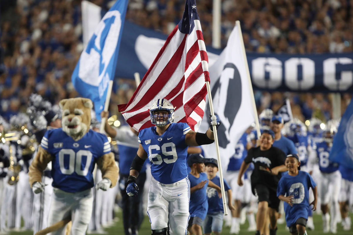 BYU offensive lineman Tristen Hoge (69) carries a U.S. flag onto the field before the team's NC ...