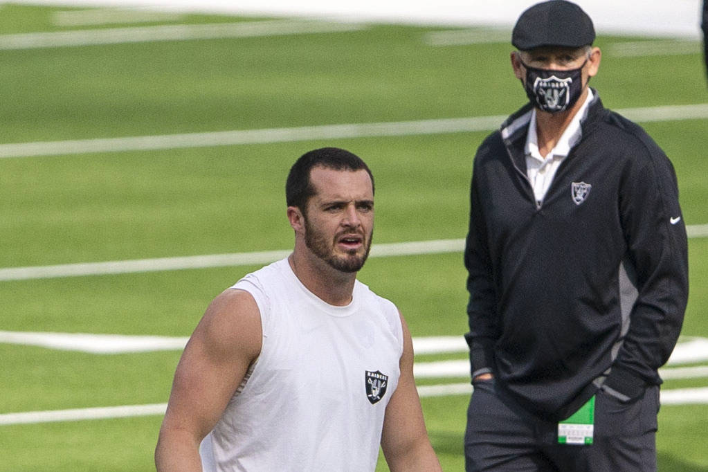 Las Vegas Raiders general manager Mike Mayock, right, looks on as quarterback Derek Carr warms ...