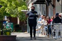 A member of the wait staff delivers food to outdoor diners along the sidewalk at the Mediterran ...