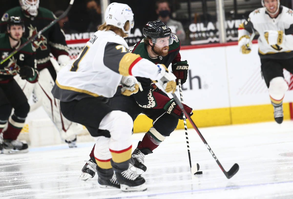 Arizona Coyotes' Phil Kessel (81) skates with the puck under pressure from Golden Knights' Will ...