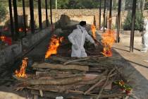 A family member performs the last rites of a COVID-19 victim at a crematorium in Jammu, in Jamm ...