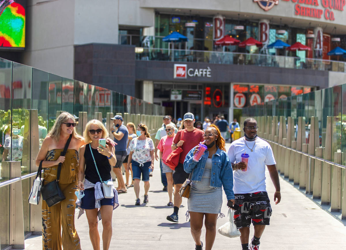 Tourists cross the pedestrian bridge connected to Harmon Corner on the Strip on Friday, April 3 ...