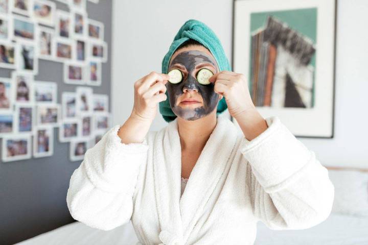 A woman puts cucumbers over her eyes as she sits up with a charcoal facial mask on her. (The Pe ...