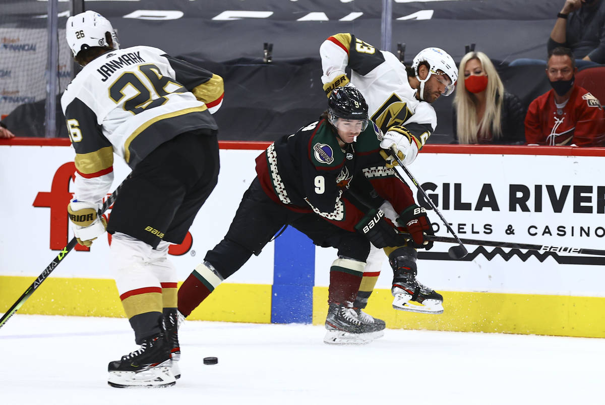 Golden Knights' Alec Martinez (23) passes the puck under pressure from Arizona Coyotes' Clayton ...