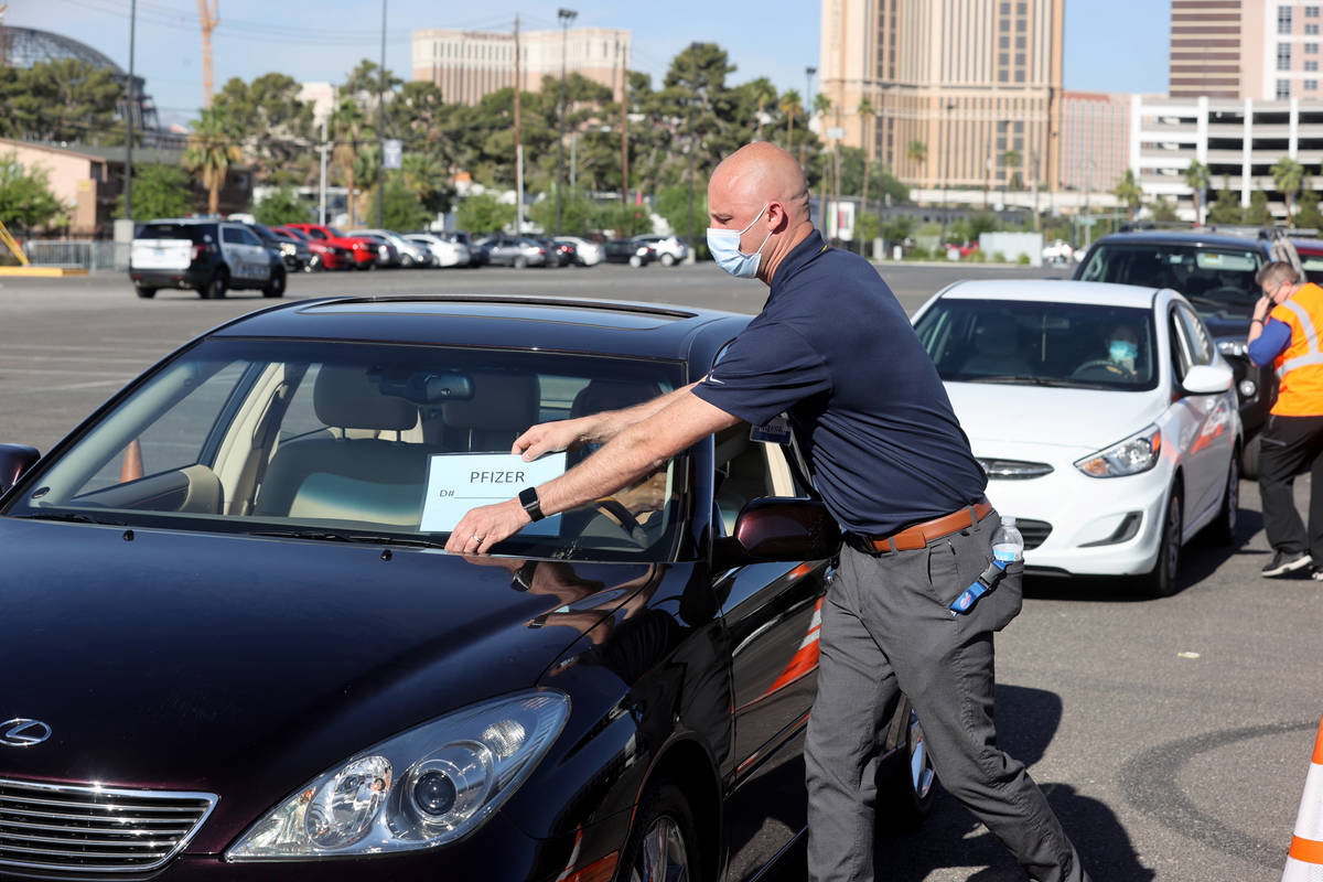 Travis Haldeman, a Clark County Fire Department engineer, marks cars during a drive-thru COVID- ...