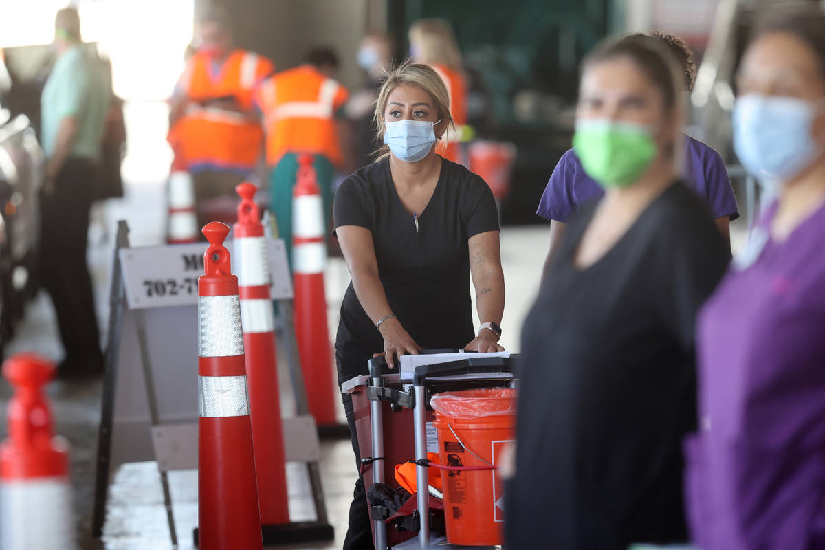 Workers prepare to give shots during a drive-thru COVID-19 vaccine clinic in the Bronze Lot at ...