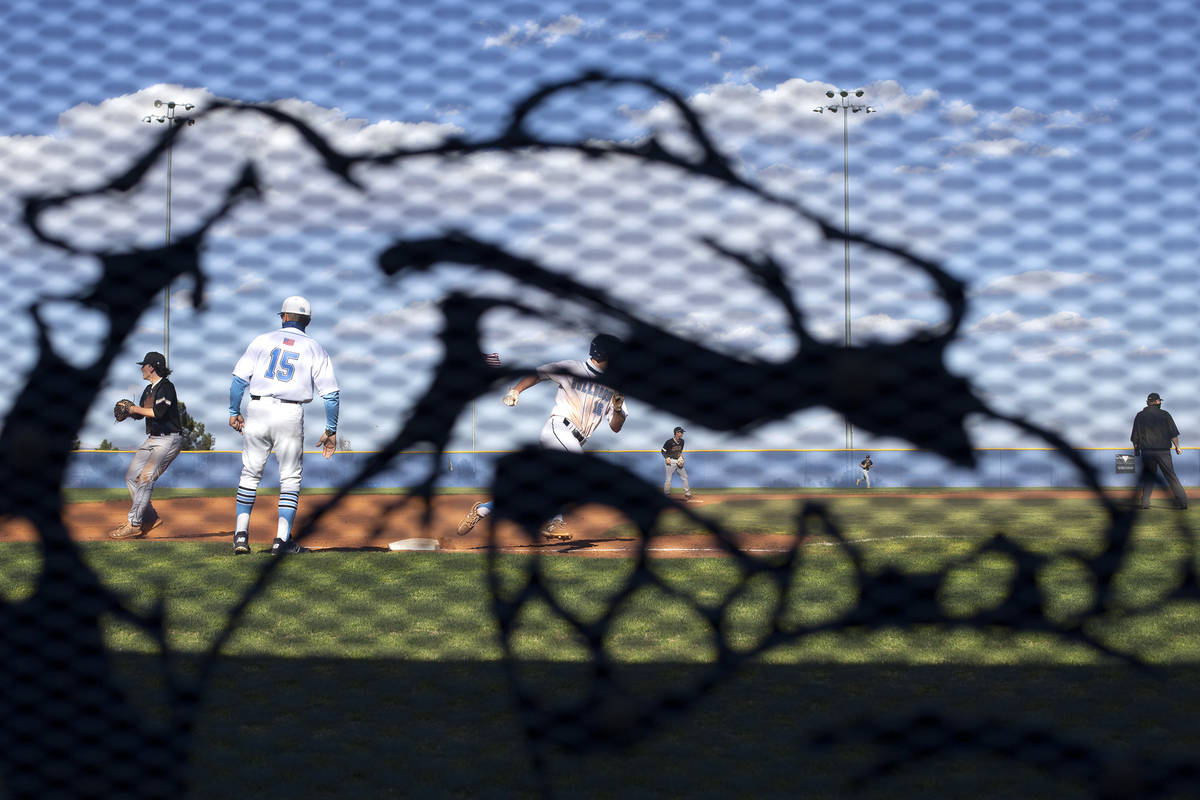 Centennial High School's baseball coach Charlie Cerrone coaches at third base as seen through t ...