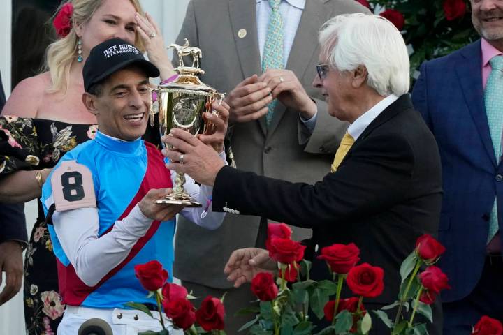 Trainer Bob Baffert hands the winner's trophy to jockey John Velazquez after they victory with ...
