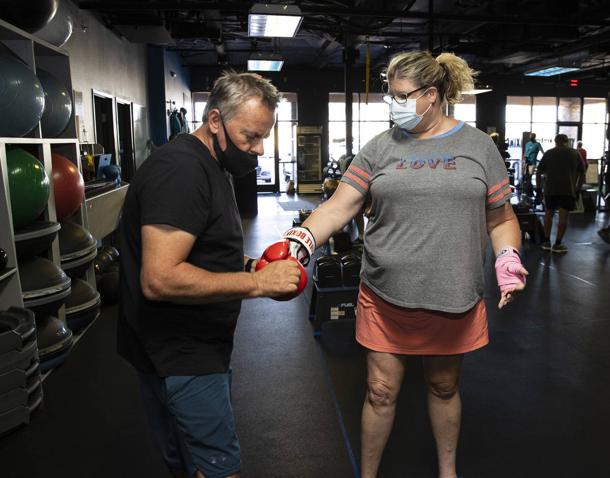 Robert Vlcek, a volunteer trainer, helps Gwen Vaughn, 48, put her boxing gloves on prior to her ...