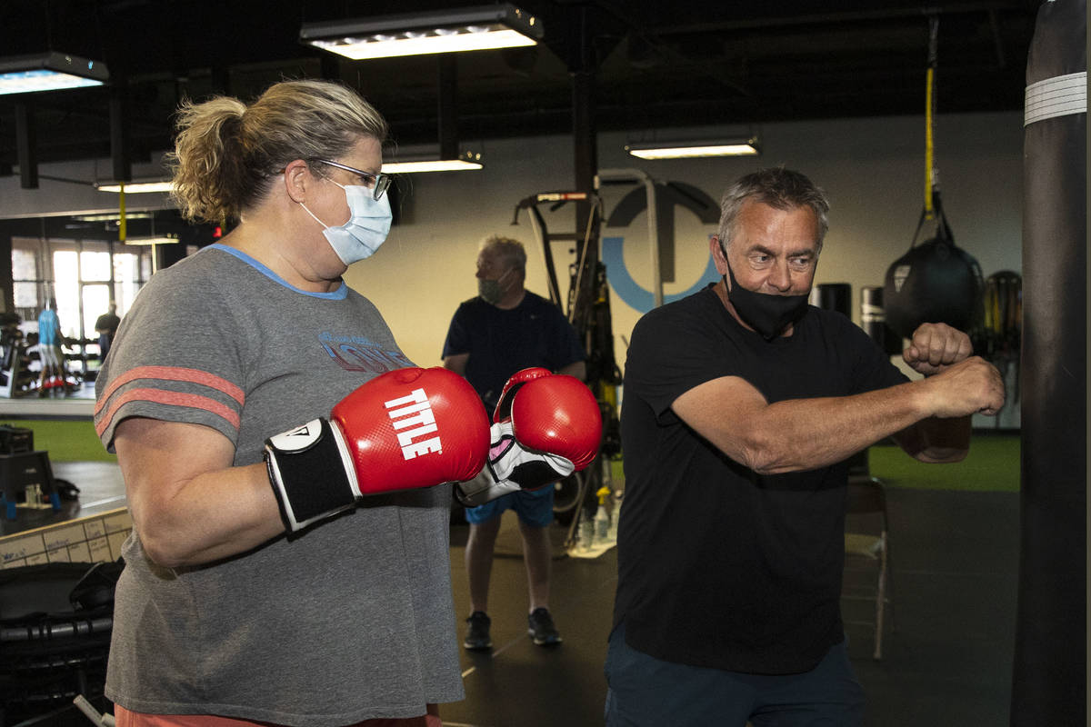 Robert Vlcek, a volunteer trainer, demonstrates to Gwen Vaughn, 48, how to punch the bag during ...