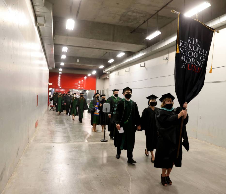 Student Marshal and Director of Student Affairs Ann Diggins leads the first graduating class of ...