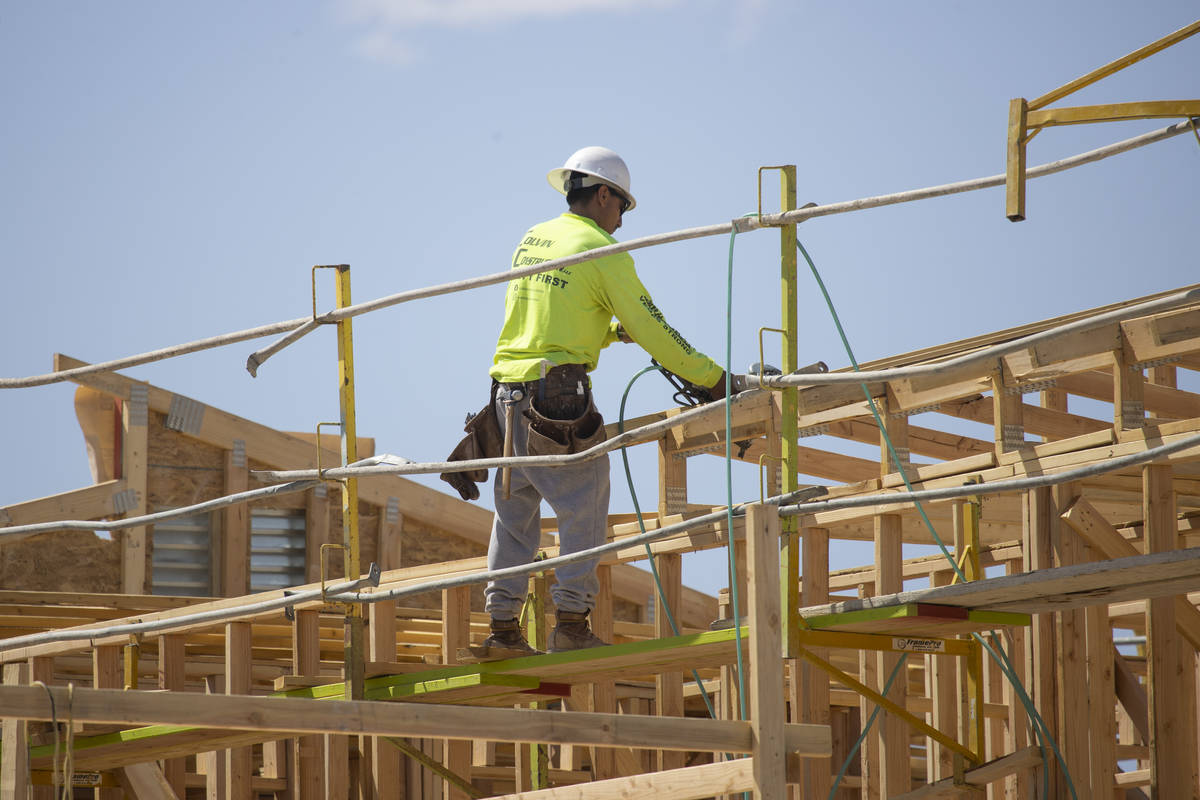 A construction worker builds the roof of a home near W Elkhorn Road and N Aviary Way in North L ...