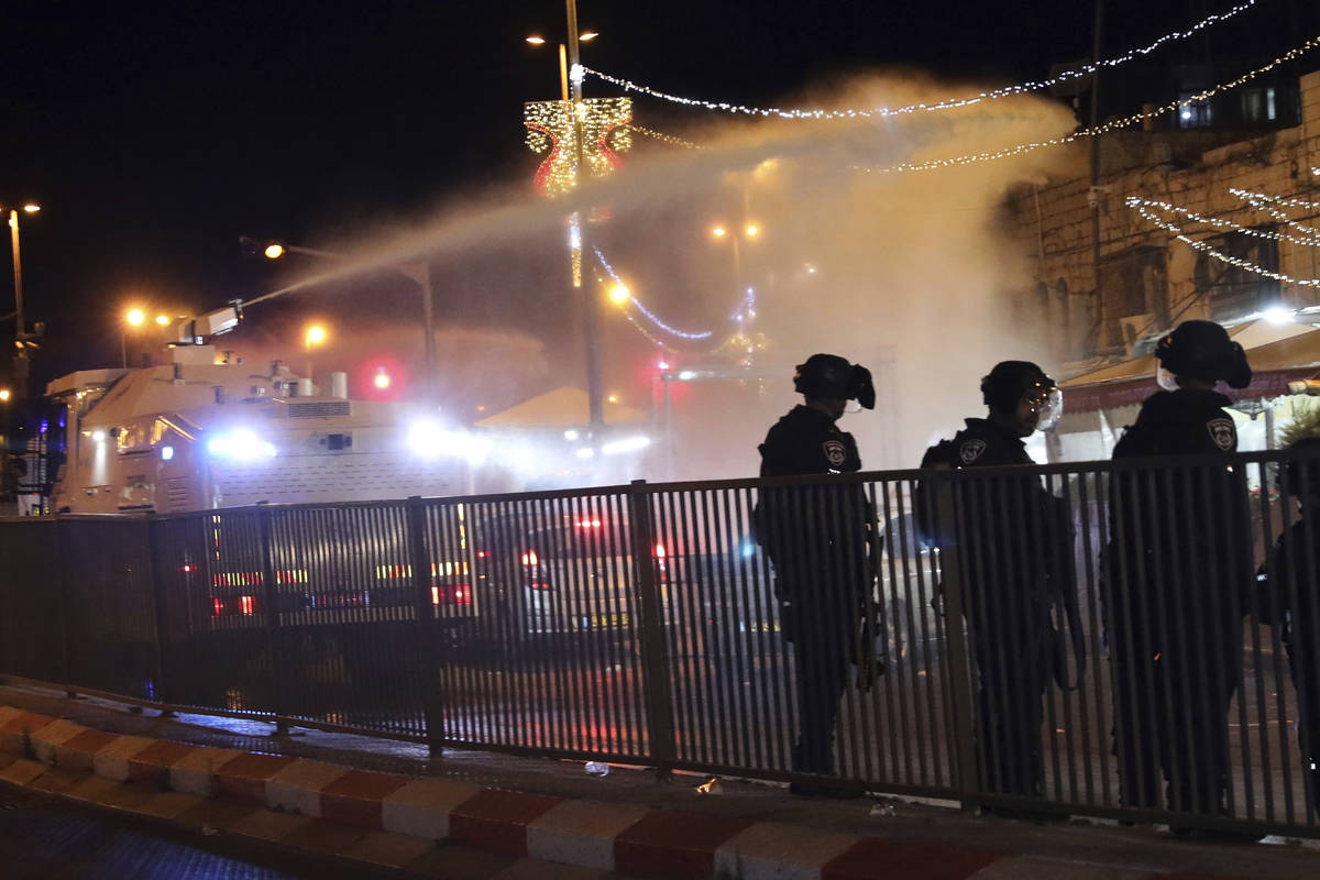 Israeli police use a water cannon to disperse Palestinian protesters from the area near the Dam ...