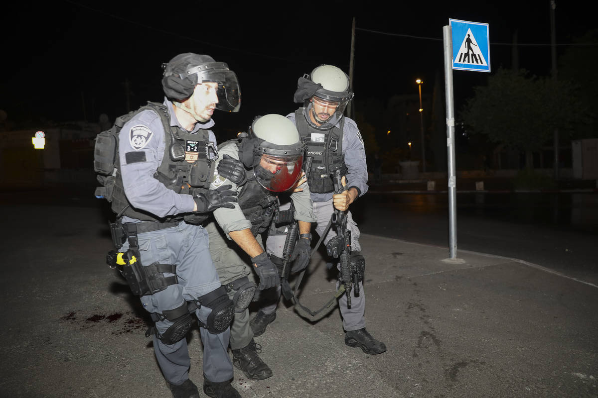 An injured Israeli police officer is helped during clashes with Palestinian protesters, in east ...