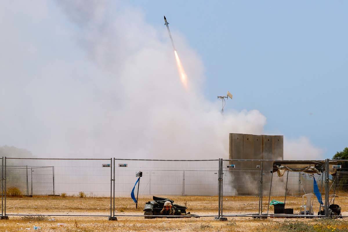 A Israeli soldier takes cover as an Iron Dome air defense system launches to intercept a rocket ...