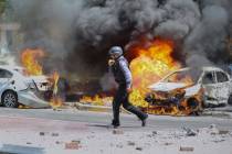 An Israeli firefighter walks next to cars hit by a missile fired from Gaza Strip, in the southe ...