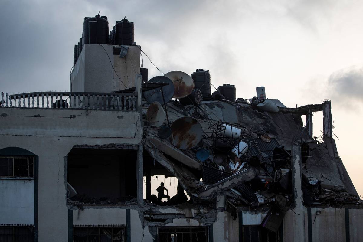 A Palestinian searches for survivors under the rubble of a destroyed rooftop of a residential b ...