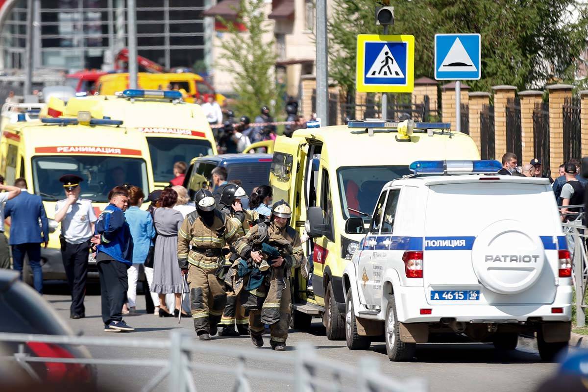 Firefighters walk past ambulances and police cars and a truck parked at a school after a shooti ...